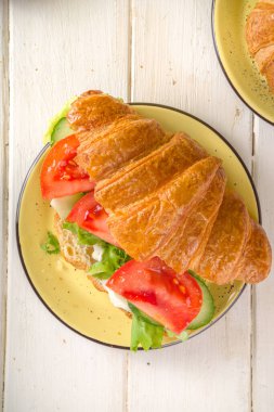 Taze sebzeli kruvasan sandviçi. Marul, domates, salatalık. Vitamin diyeti yaz veya bahar atıştırması, kahvaltı. Sarı arkaplan kopyalama alanı