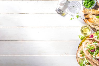 Akdeniz yemekleri. Doner Kebap, Taco, Shawarma, Yunan jiroskop sandviçi, kızarmış tavuk eti, taze sebze, tsatziki sosu. Güneşli beyaz tahta masa kopyalama alanı