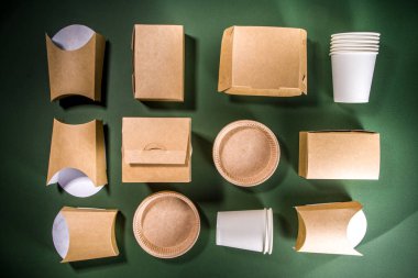 Karton fast food ve içecek ambalaj konsepti. Çevre dostu, yeşil arka planda çeşitli yiyecek konteynerleri. 