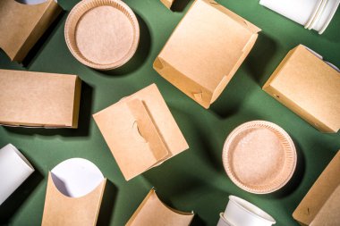 Karton fast food ve içecek ambalaj konsepti. Çevre dostu, yeşil arka planda çeşitli yiyecek konteynerleri. 