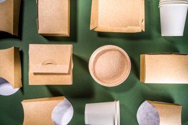 Karton fast food ve içecek ambalaj konsepti. Çevre dostu, yeşil arka planda çeşitli yiyecek konteynerleri. 