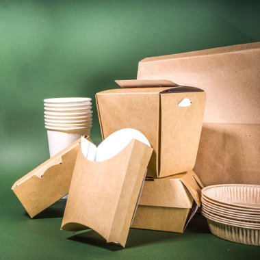 Karton fast food ve içecek ambalaj konsepti. Çevre dostu, yeşil arka planda çeşitli yiyecek konteynerleri. 