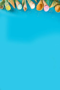 Dondurmalı waffle külahında çeşitli parlak renkli dondurma seti. Çikolatalı, yabanmersinli, şam fıstıklı, trend turkuaz arka planda ve tropikal palmiye yapraklı.