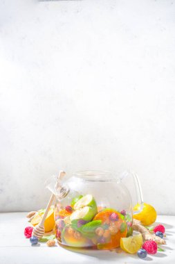 Çaydanlıkta meyve ve çilek çayı. Limonlu, naneli, yabanmersinli, zencefilli, portakallı, elmalı sıcak içecek. Beyaz ahşap arka plan fotokopi alanında sıcak aromalı buhar içeceği  