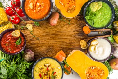 Farklı sonbahar çorbaları seti. Portakal kaselerinde çeşitli sebze çorbaları - mısır, patates, balkabağı, domates, kabak, brokoli kremalı çorba. Beyaz beton arkaplanda üst görünüm kopyalama alanı