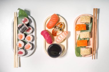 Pirinç ve balıklı suşi ruloları, beyaz arka planda soya sosu. 