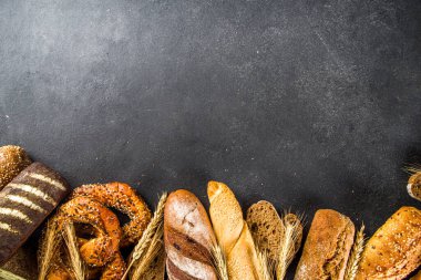 Çeşit çeşit lezzetli taze pişmiş ekmek, siyah beton arka plan üst görünüm kopya alanı