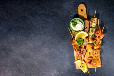 Çeşitli barbekü çeşitleri Akdeniz ızgara gıdaları - balık, karides, yengeç, midye, soslu kebap, siyah beton arka plan, kopyalama alanının üstünde