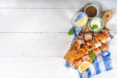 Çeşitli barbekü çeşitleri Akdeniz ızgara gıdaları - balık, karides, yengeç, midye, soslu kebap, beyaz ahşap arka plan, fotokopi alanının üstünde