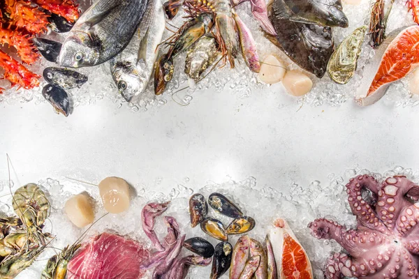 Çeşitli taze çiğ deniz ürünleri seti - ahtapot, yengeç, mürekkep balığı, karides, istiridye, midye, somon balığı limon baharatlı ton balığı, ezilmiş buzlu arka plan üst görünüm 
