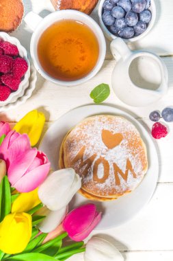 Anneler Günü Brunch Restoran Davetiyesi. Çeşitli Anneler Günü Menüleri, geleneksel kahvaltı, öğle yemeği ve içecek seti, güneşli beyaz ahşap arka planda çiçekler.