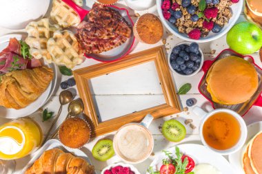 Çeşitli geleneksel kahvaltı yemekleri - domuz pastırmalı kızarmış yumurta, müsli, yulaf, waffle, gözleme, burger, kruvasan, meyve üzümü, kahve, çay ve portakal suyu, beyaz masa arkaplan fotokopisi