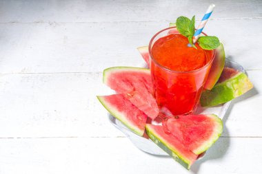 Buzlu soğuk içecek, karpuzlu mojito veya meyve suyu, beyaz ahşap bir masada küçük bir tepside taze karpuz dilimleri ile. 