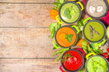 Çeşitli renkte sebze çorbaları. Küçük porsiyonlu kuşkonmaz, ıspanak, brokoli, yeşil bezelye, domates, havuç gibi çeşitli sebze kremalı çorbalar. Ahşap arkaplan kopyalama alanı üst görünümü