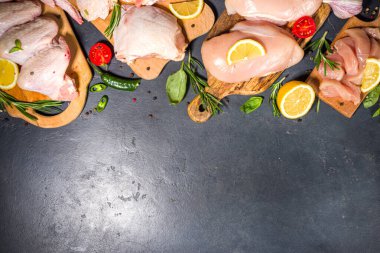 Çeşitli çiğ tavuk eti porsiyonları. Pişmemiş tavuk filetosu, but, kanatlar, şeritler ve bacaklar siyah yemek masasında baharatlı. 