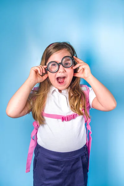 学校のコンセプトに戻る 学校招待状広告バナー 白い青の古典的な制服でかわいい小学生の女の子は 本のバックパックで 面白いメガネ カラフルな青の背景コピースペース — ストック写真