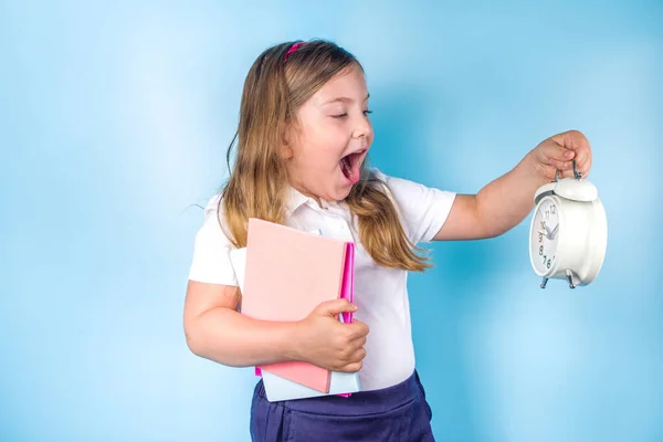 招待状 広告バナーに戻る 白い青い制服を着たかわいい小学生の女の子 目覚まし時計 学ぶ時間 学校の販売の概念 — ストック写真