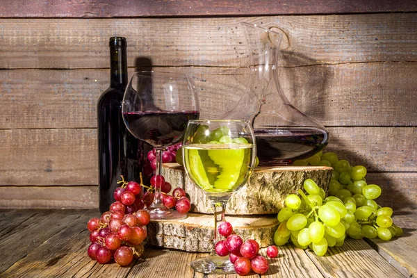日差しと影のある赤と白のワインの眼鏡 ボトルとデカンター付き ブドウの束 有機台座と木製の背景に 秋の収穫 ワイナリーのコンセプト — ストック写真