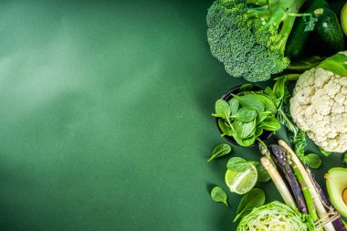 Sağlıklı diyet bahar yemekleri. Taze çiğ organik sebze çeşitleri - brokoli, karnabahar, kabak, salatalık, kuşkonmaz, ıspanak, avokado, koyu yeşil arka planda lahana.
