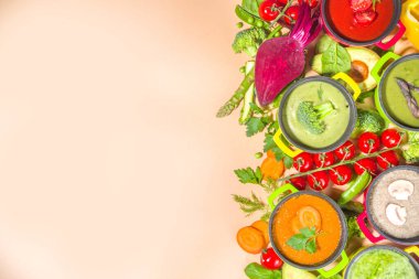 Çeşitli renkli sebze çorbaları. Küçük porsiyonlu kuşkonmaz, ıspanak, brokoli, yeşil bezelye, domates, havuç gibi çeşitli sebze kremalı çorbalar. Bej sıcak renkli arkaplan fotokopi alanı üst görünümü