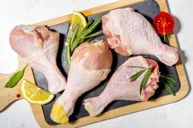  Çiğ tavuk budu, baharatlı but ve yemek pişirmek için otlar, beyaz masa arkaplanı fotokopi alanı