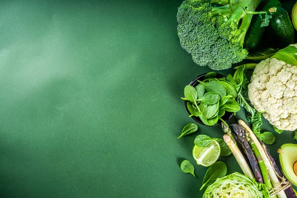 Sağlıklı diyet bahar yemekleri. Taze çiğ organik sebze çeşitleri - brokoli, karnabahar, kabak, salatalık, kuşkonmaz, ıspanak, avokado, koyu yeşil arka planda lahana.