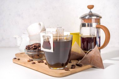 Poşetten taze demlenmiş bir fincan kahve. Süslü kahve çeşitleri, beyaz mutfak masasında fincanlar, kopyalama alanı