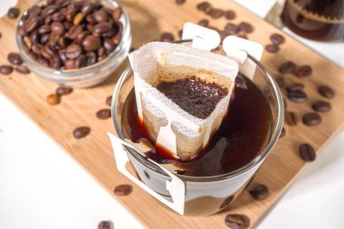 Poşetten taze demlenmiş bir fincan kahve. Süslü kahve çeşitleri, beyaz mutfak masasında fincanlar, kopyalama alanı