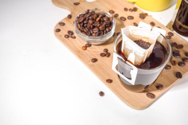 Poşetten taze demlenmiş bir fincan kahve. Süslü kahve çeşitleri, beyaz mutfak masasında fincanlar, kopyalama alanı