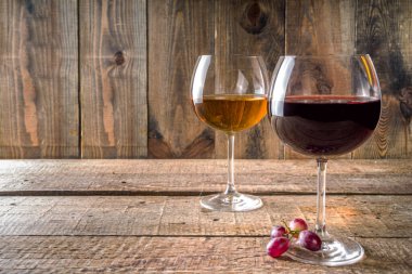 Şaraplı bardaklar. Kırmızı ve beyaz şarap bardaklarda, ahşap arka planda üzüm fotokopi alanı.