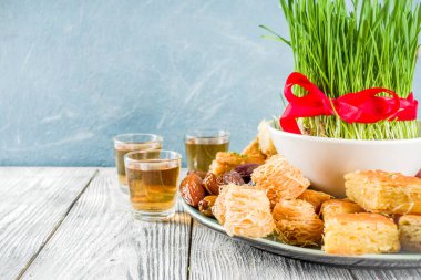 Nowruz tatilin kutlu olsun. Nowruz tatlılarını ve tedavilerini kutluyoruz- baklava, çeşitli kurutulmuş meyveler, fındıklar, tohumlar, yeşil çimenli ahşap arka plan, kopyalama alanı
