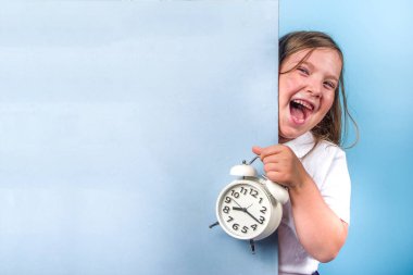 Okula dönmek, davetiye, reklam afişi. Beyaz mavi üniformalı, kitapları ve çalar saati olan tatlı bir ilkokul öğrencisi. Öğrenme zamanı, okul satış konsepti