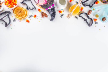 Cadılar Bayramı zencefilli kurabiye pişirme arka planı. Sonbahar tatili pişirme konsepti, malzemeler, baharatlar, cadılar bayramı sembolü kurabiye kesiciler - balkabağı, hayalet, yarasa, cadı şapkası, üst görünüm beyaz masa kopyalama alanı