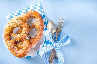 October fest concept. Oktoberfest table setting background, plate fork spoon with traditional napkin, served at event, bar menu flatlay, colorful blue table copy space top view