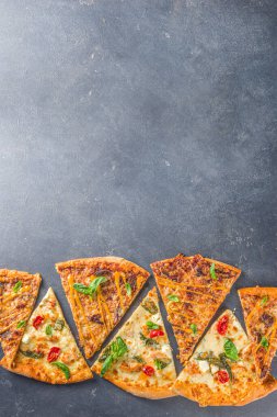 Çeşitli İtalyan geleneksel Amerikan pizza dilimleri. Koyu gri arka planda leziz pizza dilimleri, üst görünüm düz yatak.