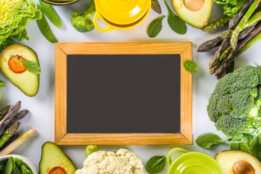 Çeşitli organik yeşil baharatlı sebze malzemeleri beyaz mutfak masasında porsiyonlu tencereler, üst manzara. Diyet sağlıklı çorba, güveç yemek hazırlama konsepti