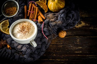 Sonbahar tatlısı, Chai Buttered Rum, Balkabağı Turtası veya Baharatlı Kahve Latte. Geleneksel latte fincanı, baharatları ve eski süveteri olan, kırsal ahşap arka planda rahat bir sonbahar arkaplanı.