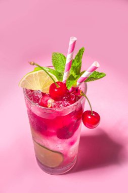 Soğuk ve ferahlatıcı bir yaz içeceği. Kirazlı kola, limonata, limonlu mojito limonata kokteyli ve renkli pembe arka planda kirazlar.