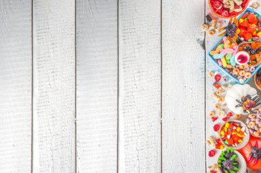 Cadılar Bayramı şekerleri ve şekerleri. Çeşitli çocuklar Cadılar Bayramı için şeker, kahvaltılık gevrek, şeker, yemek kutusu ve kova, düz fotokopi alanı üst görünümü.