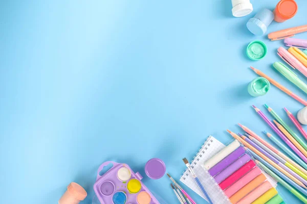 Online study and drawing, distantly painting class. Various colorful stationery and supplies for drawing. paints, pastels, pencils, brushes, tablet on blue background. Flatlay top view  copy space