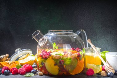 Çaydanlıkta meyve ve çilek çayı. Limonlu, naneli, yabanmersinli, zencefilli, portakallı, elmalı sıcak içecek. Koyu mavi arkaplan fotokopi alanında sıcak aromalı buhar içeceği  