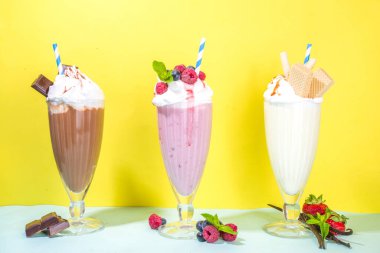 Yaz ferahlatıcı içecekler, milkshake 'ler, dondurmalı çılgın milk shake' ler, böğürtlen, vanilya, çikolata. Parlak mavi bir arka planda 