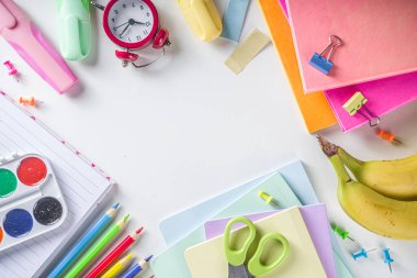 Okul konseptine geri dönelim. Okul malzemeleri ve kırtasiye malzemeleriyle beyaz arka planda düz çizgi, üst görünüm kopya alanı