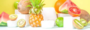 Yaz kompozisyonu, çeşitli tropikal meyveler, modern, parlak sarı arka planda podyumlar, kopyalama alanı. Tatil ve tatil, sağlıklı gıda konsepti boşluğu kopyalamak