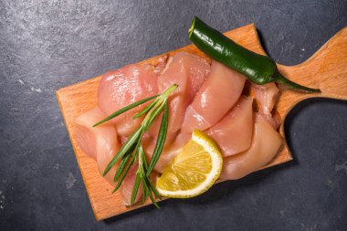 Çiğ çiğ tavuk eti şeritleri, taze çiğ göğüs filetosu yemek tahtasında beyaz masa arkaplan manzarası