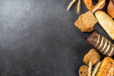 Çeşit çeşit lezzetli taze pişmiş ekmek, siyah beton arka plan üst görünüm kopya alanı