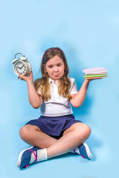 学校に戻るライフバランスの概念 目覚まし時計と蓮の位置に彼女の手のノートブックの大規模なスタックとかわいい白人ブロンドの女の子は バランスのとれた重み カラフルな青の背景 — ストック写真
