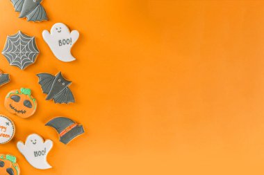 Cadılar Bayramı, arkaplanda şekerli zencefilli kurabiye ve şekerlemeler, konsept ya da şeker konsepti üst görünüm fotokopi alanı, modaya uygun parlak turuncu arkaplan