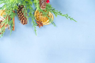 Noel kış açık mavi arka planı, köknar ağacı ladin dalları, çam kozalakları, kurutulmuş portakal, baharatlar, kış kokteylleri için malzemeler, dekorasyonlar, düz üst görünüm kopya alanı