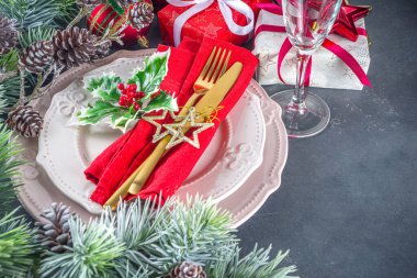 Tabaklar, şampanya kadehleri, Noel hediye kutuları ve süslemeler, köknar ağacı dalları, siyah beton arka plan fotokopi alanı üst görünümü